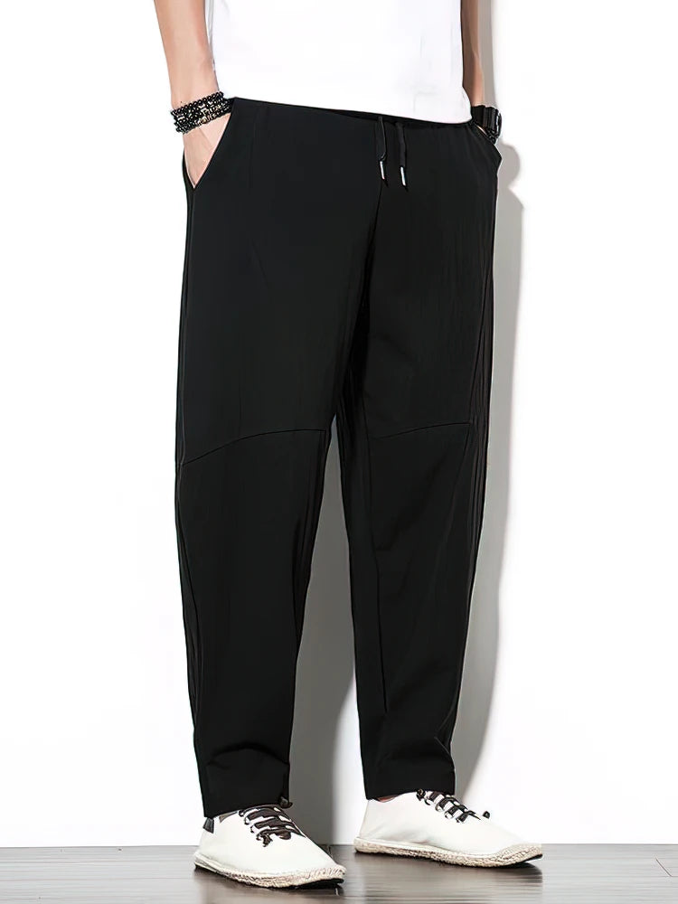 Person wearing black pants and white sneakers on a white background