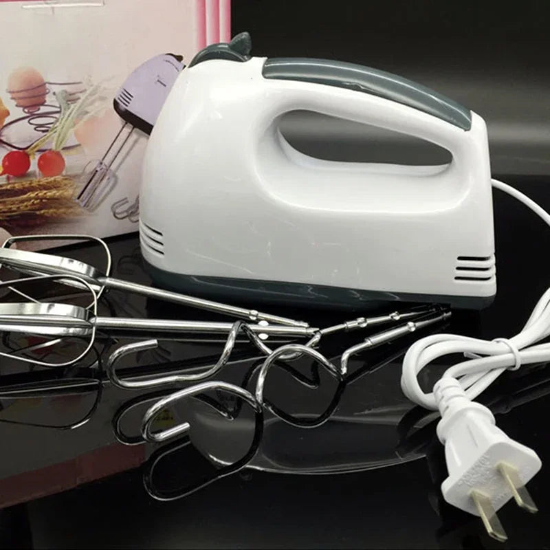 Hand mixer with attachments on a reflective surface