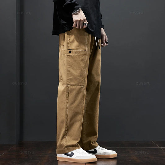 Person wearing tan pants and white sneakers against a dark background