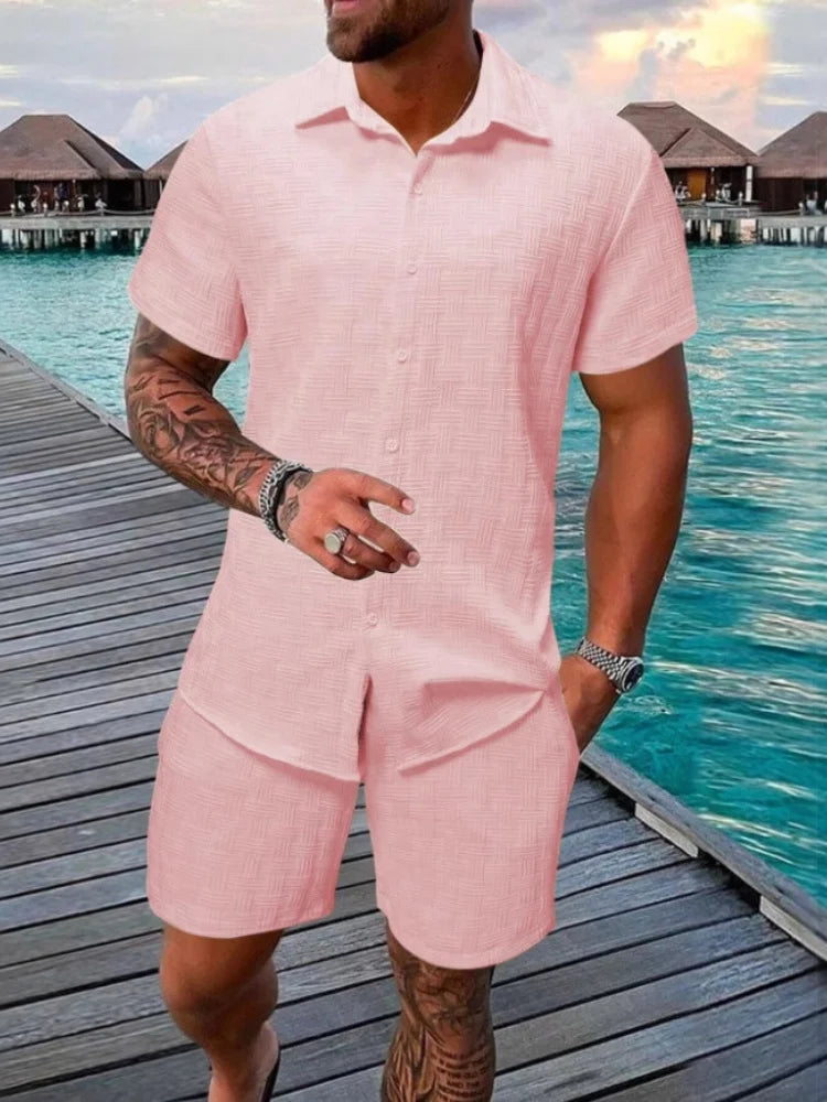 A man wearing a white short-sleeved shirt and matching shorts with a drawstring closure, standing near a poolside.