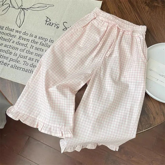 Pink checkered shorts on a wooden surface with a book in the background