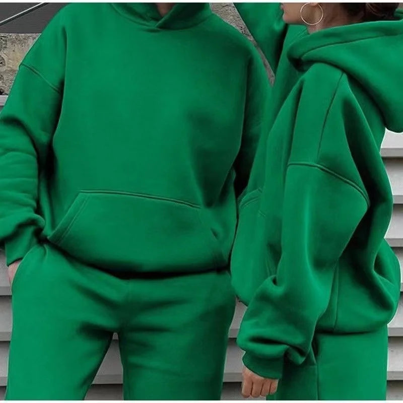 Two people wearing green hoodies and pants sitting on steps.