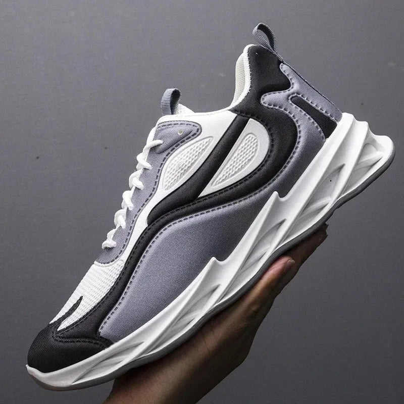 Gray and black sneaker held by a hand against a dark background