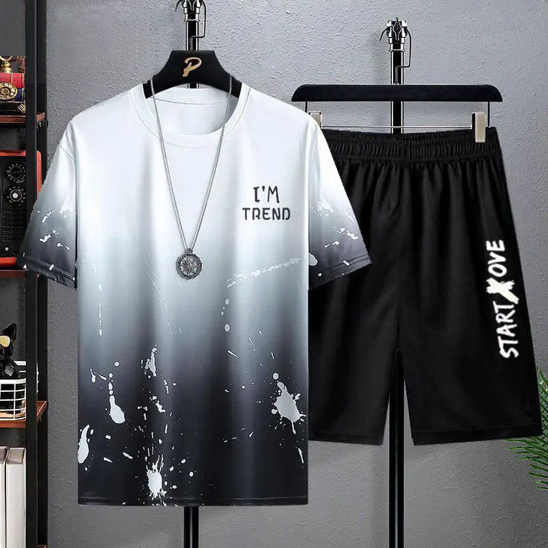 Gradient t-shirt with splatter design and black shorts on hangers against a gray background
