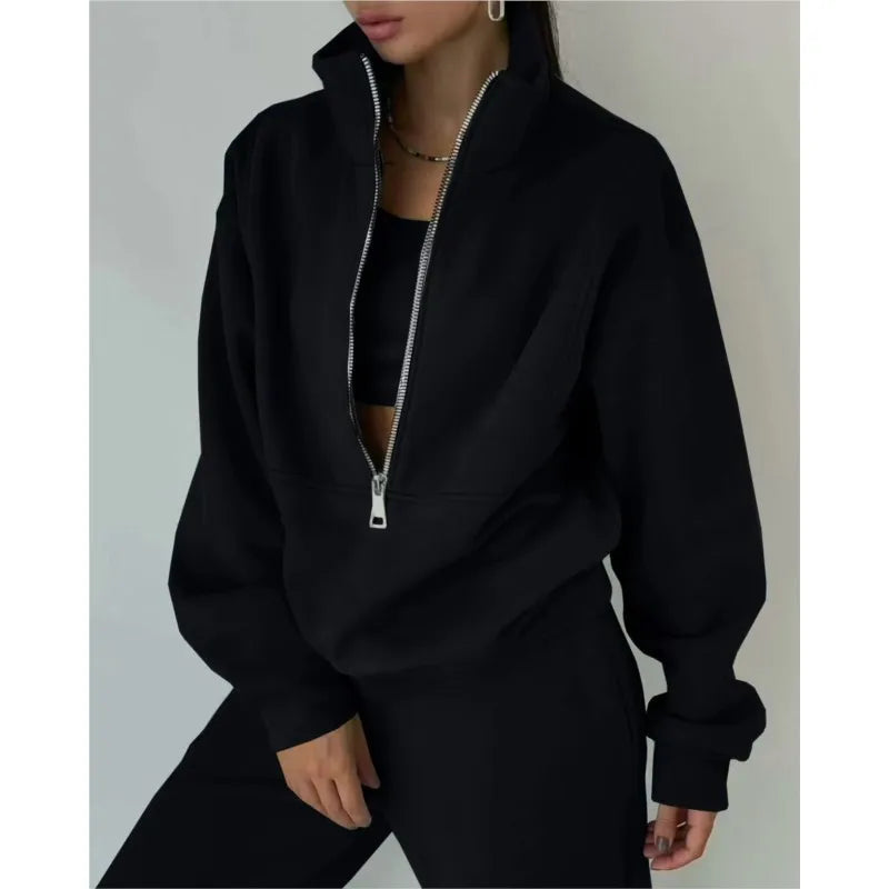 Person wearing a black zip-up hoodie against a neutral background