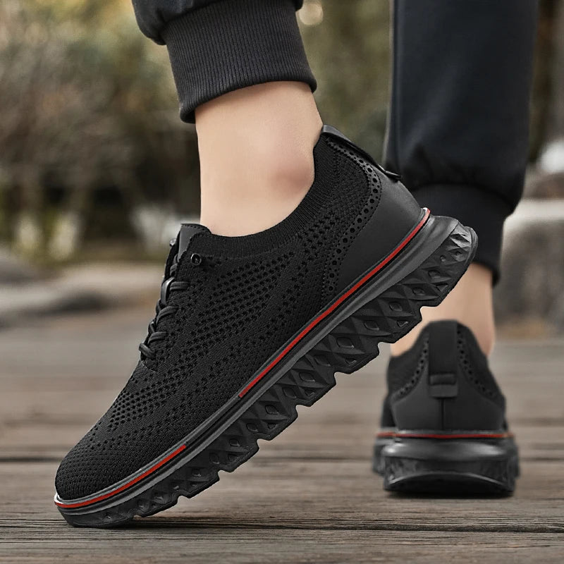 Black sneakers with red accents worn by a person on a wooden floor.