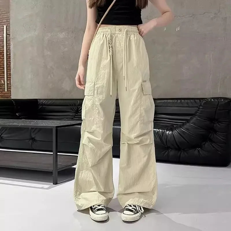 Person wearing beige cargo pants in a minimalistic room with a black sofa.