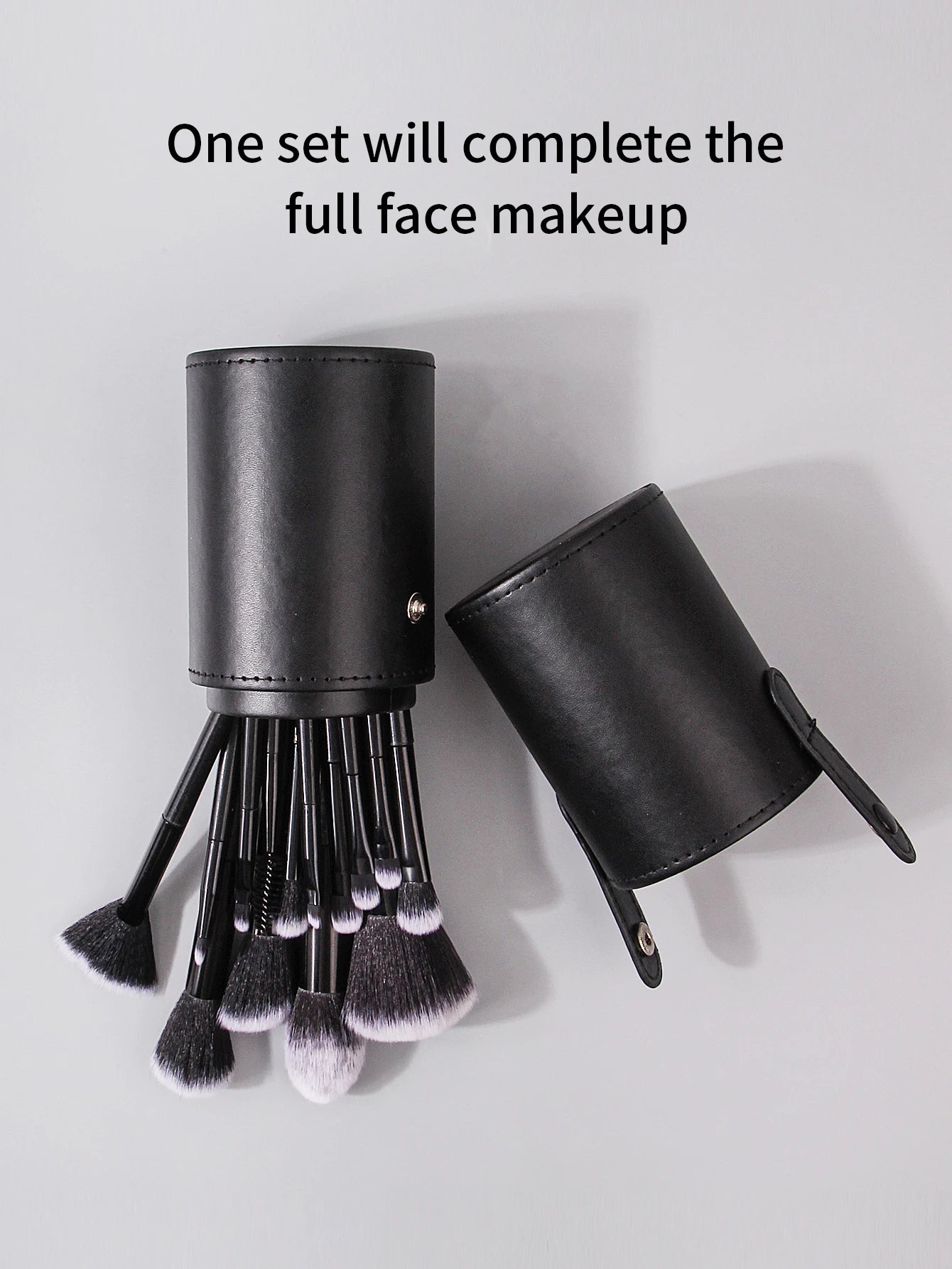 Set of makeup brushes in a black leather holder on a light gray background