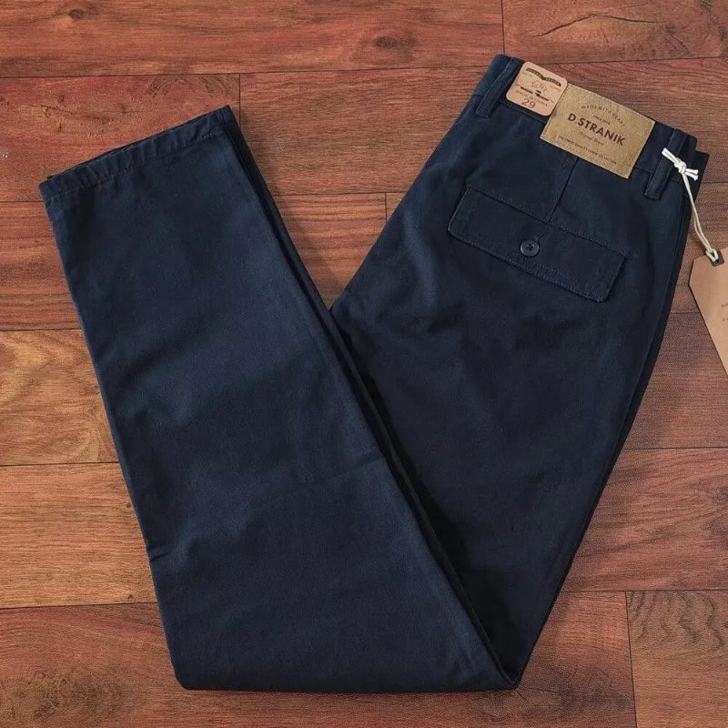 Navy pants on a wooden floor with a brand tag.
