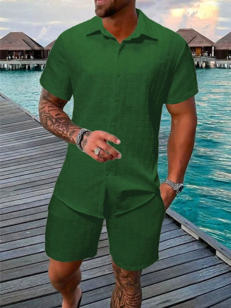 A man wearing a white short-sleeved shirt and matching shorts with a drawstring closure, standing near a poolside.