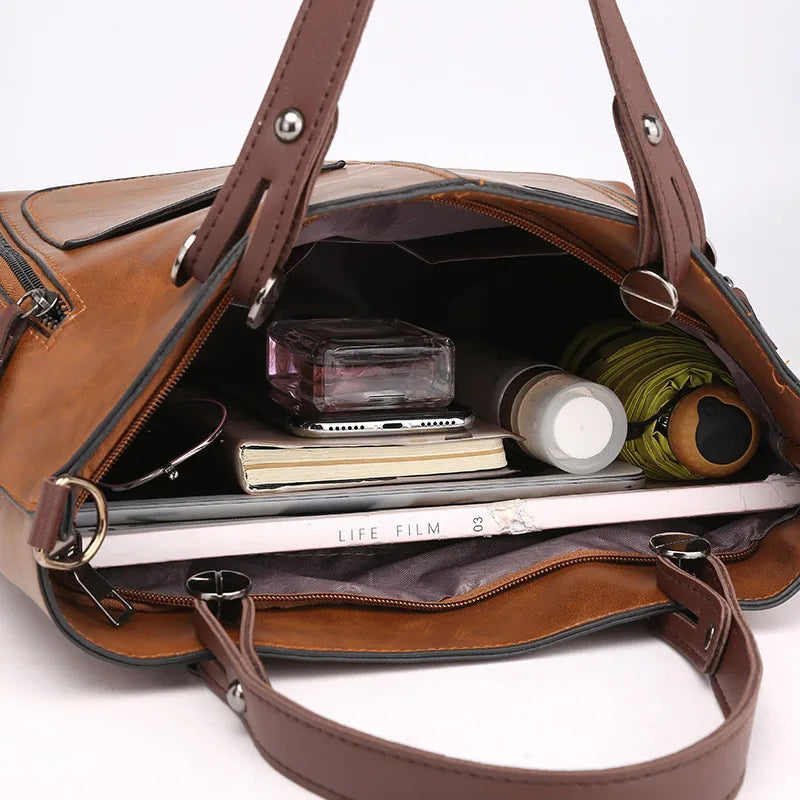 Brown leather handbag with its interior open, showing various items.