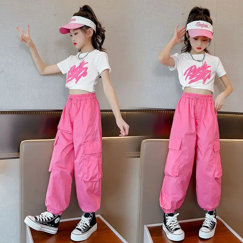 Two identical outfits of a person wearing a white crop top with pink text, pink cargo pants, and black sneakers on a neutral background.
