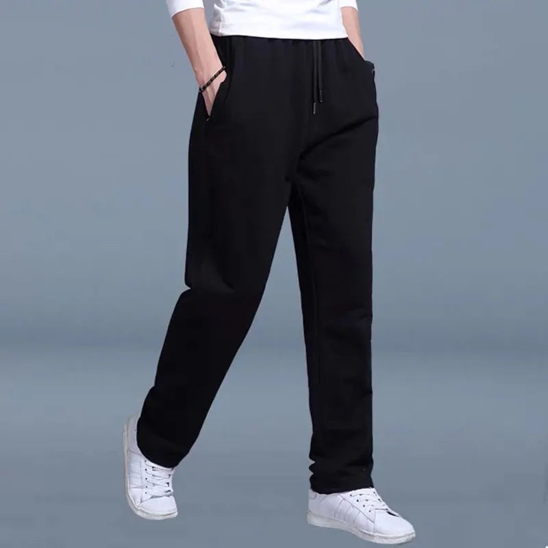 Person wearing black pants and white sneakers on a gray background