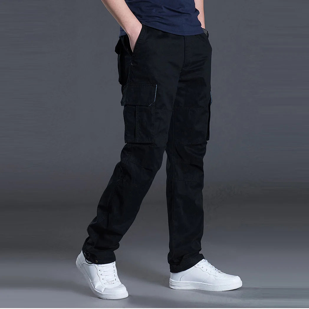 Person wearing black cargo pants and white sneakers on a gray background