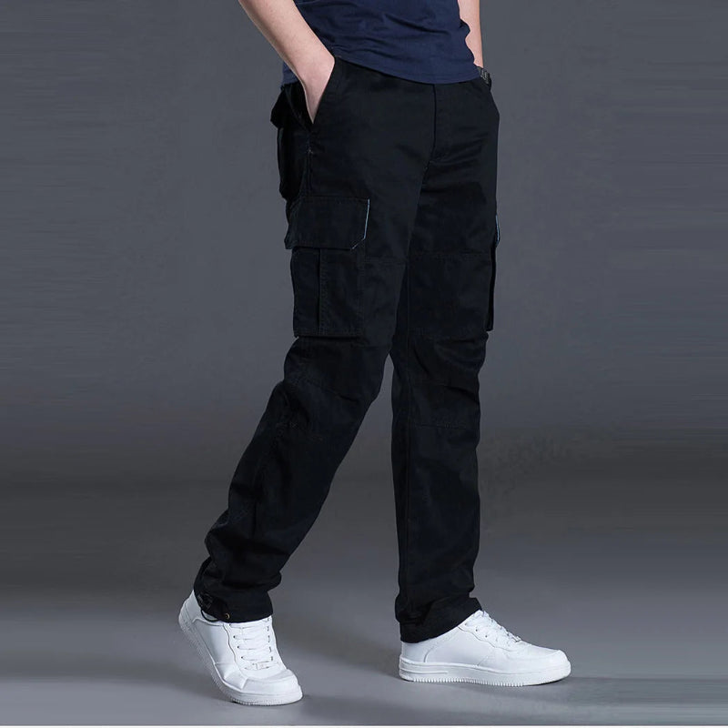 Person wearing black cargo pants and white sneakers on a gray background