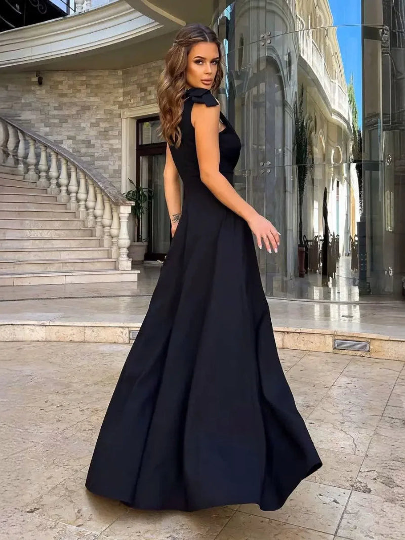 Woman in a black evening gown standing in front of a building entrance.