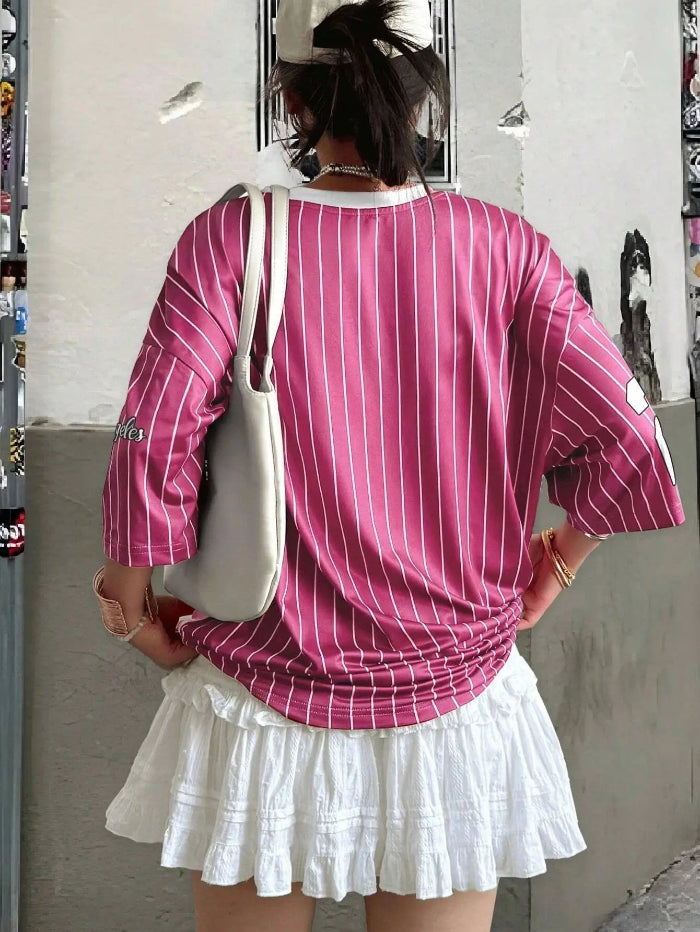 Man and woman wearing matching short-sleeved V-neck T-shirts with bold “23” digital print, standing in a sunny urban setting with sporty accessories back pink 03