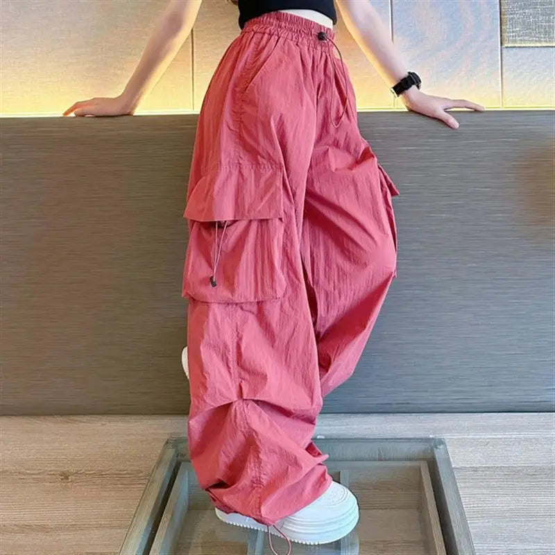 Person wearing pink layered pants and white sneakers in a minimal indoor setting