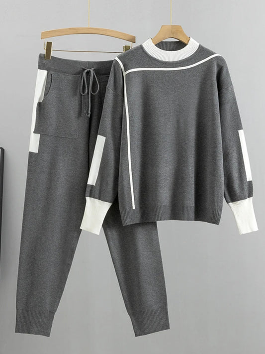 Gray tracksuit with white accents on hangers against a gray background