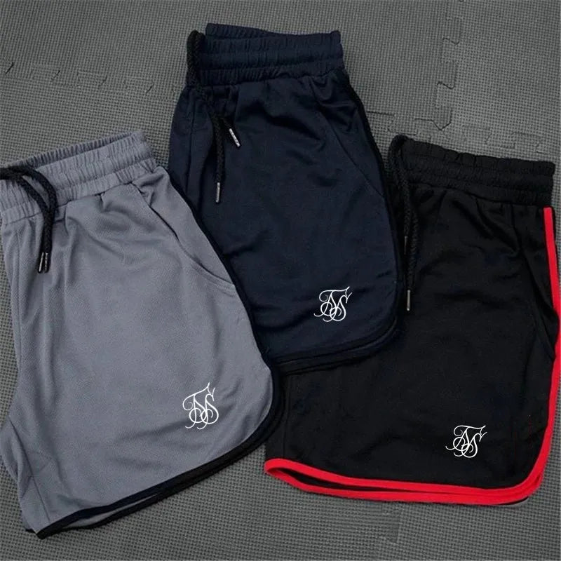 Three pairs of shorts in gray, black, and black with red trim on a textured surface.