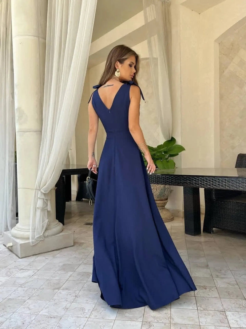 Woman in a blue evening gown standing in an elegant indoor setting.