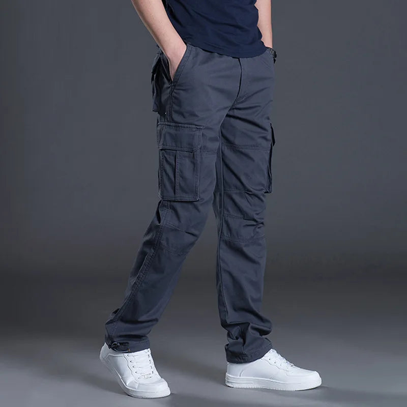 Person wearing dark blue cargo pants and white sneakers on a gray background