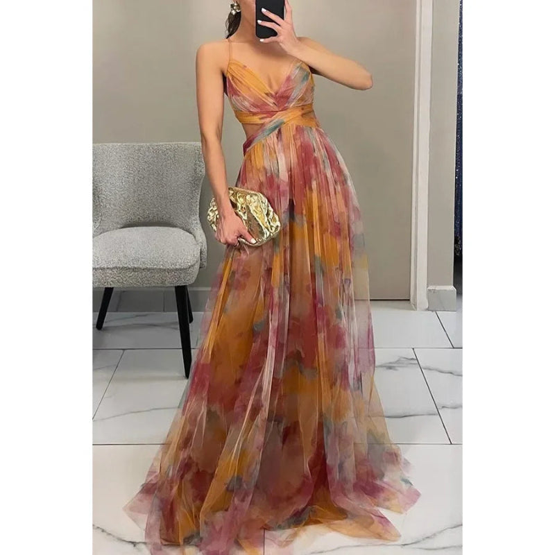 Woman wearing a colorful floral dress holding a gold clutch in a room.