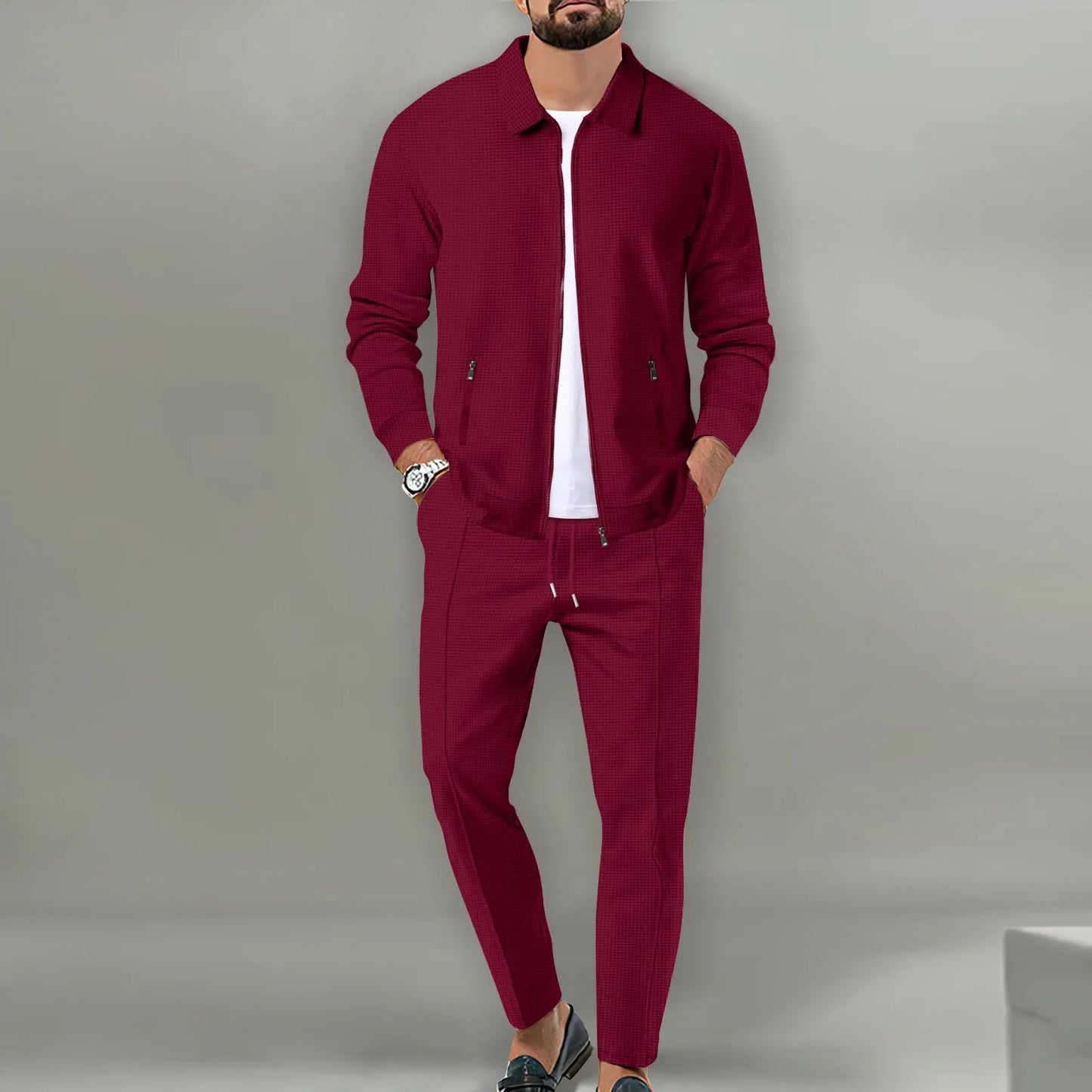 Man wearing a burgundy tracksuit against a gray background