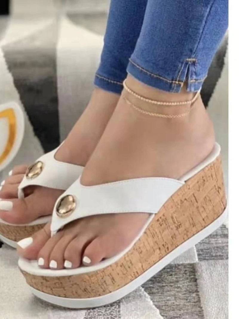 White wedge sandals with gold accents worn with blue jeans.