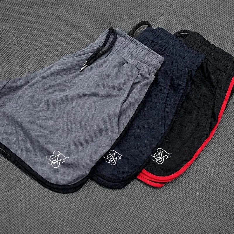 Three pairs of shorts in gray, navy, and black with red accents on a textured surface.