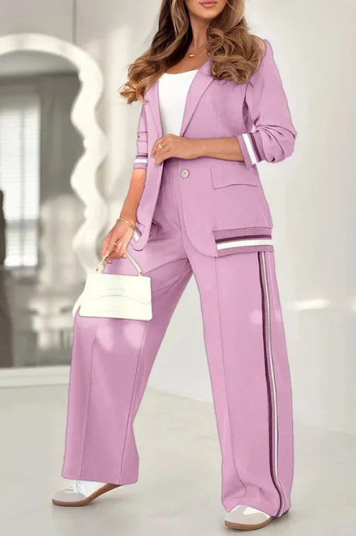 Woman wearing a pink suit with a white handbag indoors.