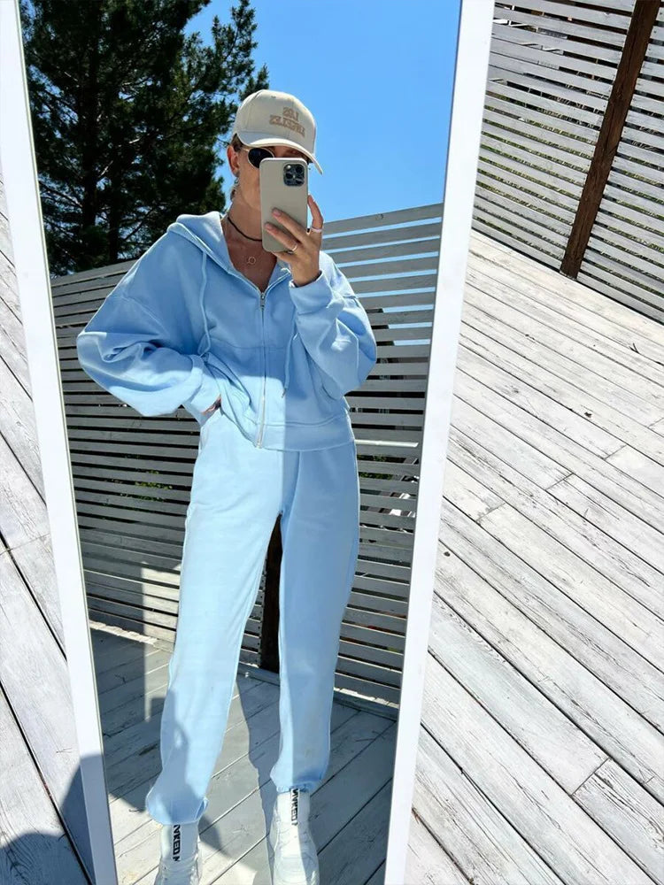 Person wearing a light blue outfit taking a mirror selfie outdoors.