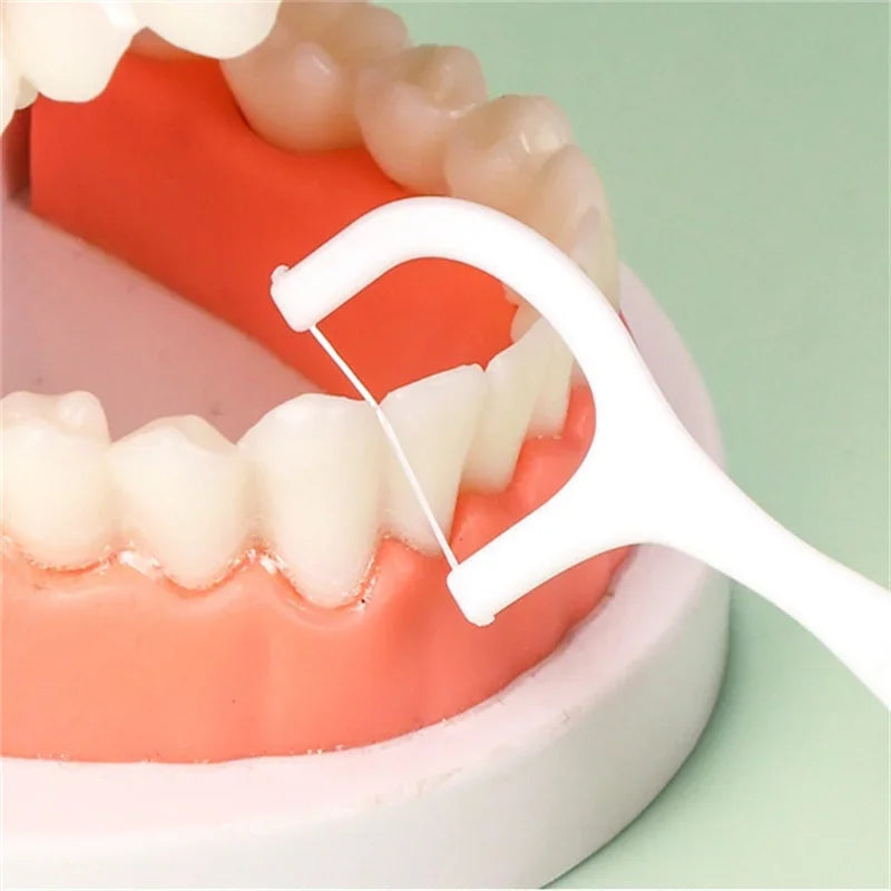 Close-up of dental floss being used between teeth on a green background