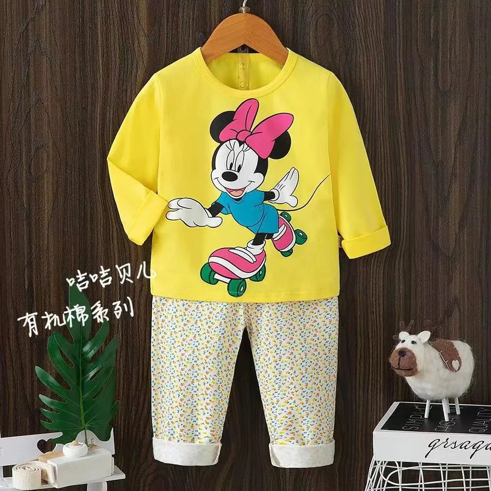 Children's outfit with yellow top and patterned pants on a wooden background