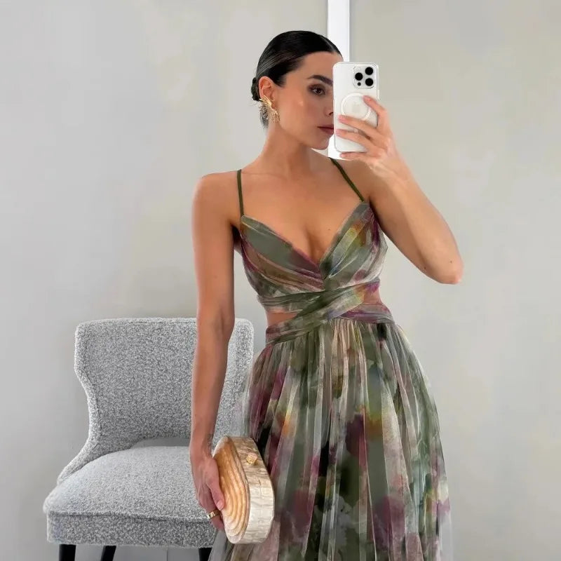 Woman taking a mirror selfie wearing a floral dress in a room with a gray chair.