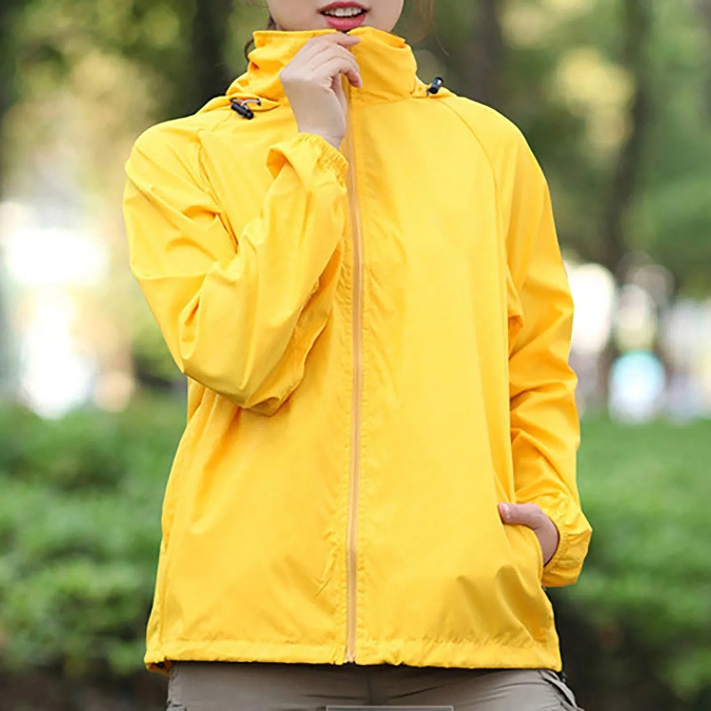 Person wearing a yellow raincoat with a blurred green background