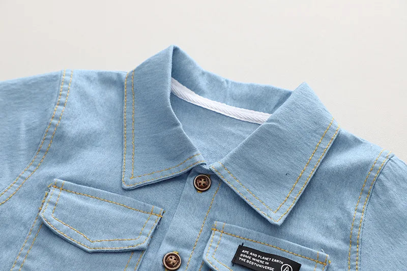 Light blue denim shirt with collar and pocket details on a light gray background