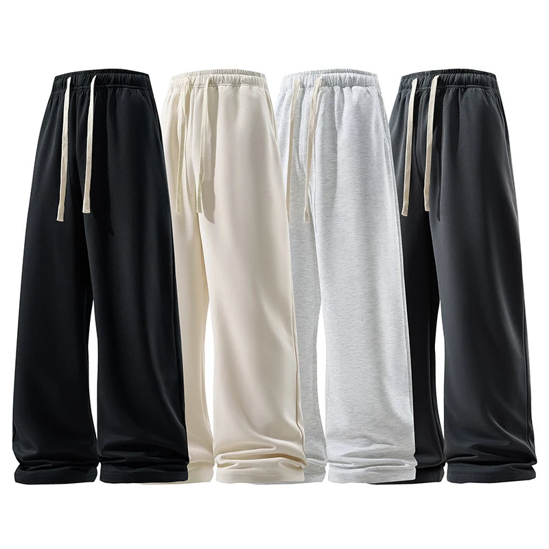 Four pairs of sweatpants in black, white, gray, and dark gray on a white background.