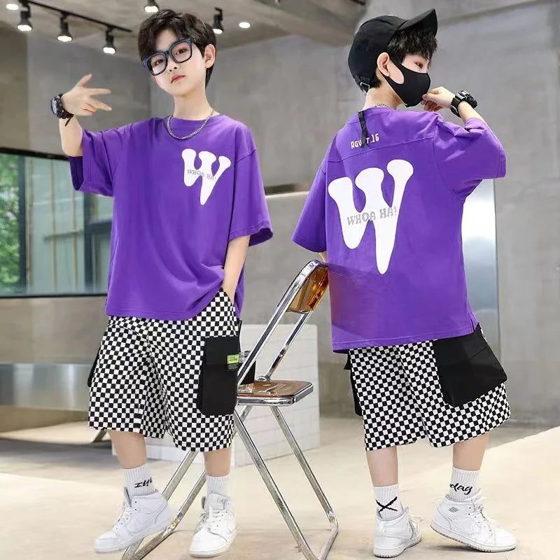 Two children wearing matching purple shirts with a white 'W' logo, black shorts, and white sneakers in an indoor setting.