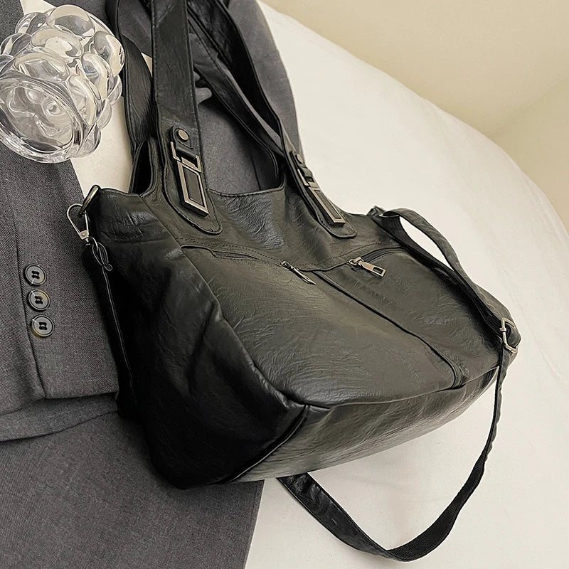 Black leather bag on a gray surface with a glass of water