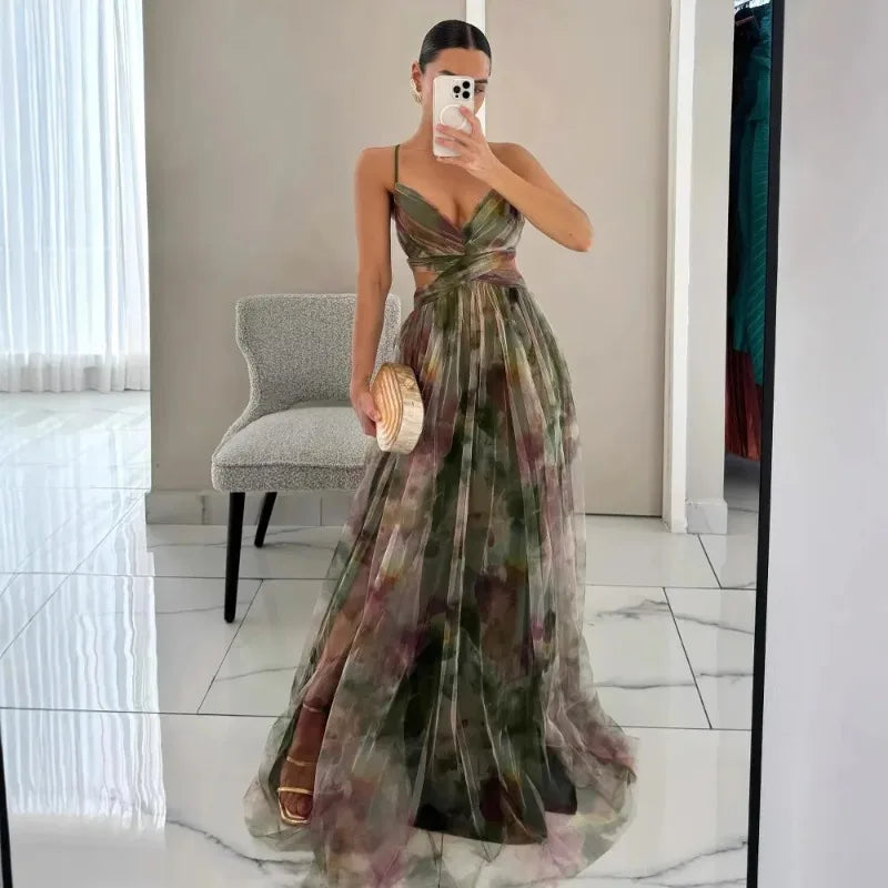 Woman in a floral dress taking a mirror selfie in a room with a chair and window.