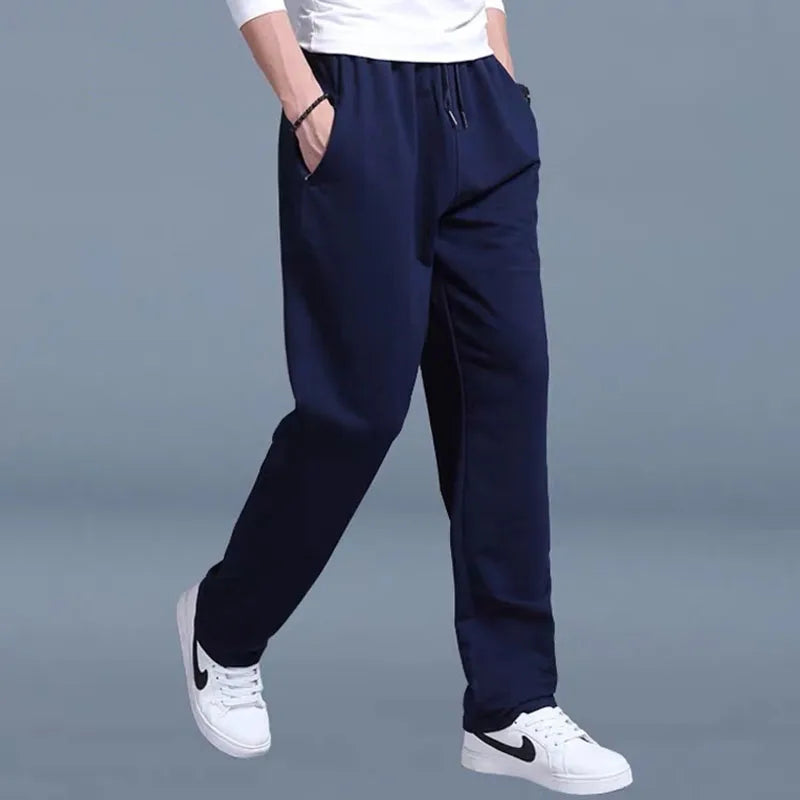 Person wearing navy blue pants and white sneakers on a gray background