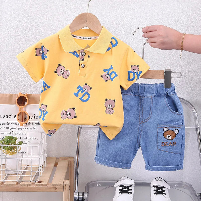 Children's yellow polo shirt with bear patterns and blue shorts on a hanger against a white background.