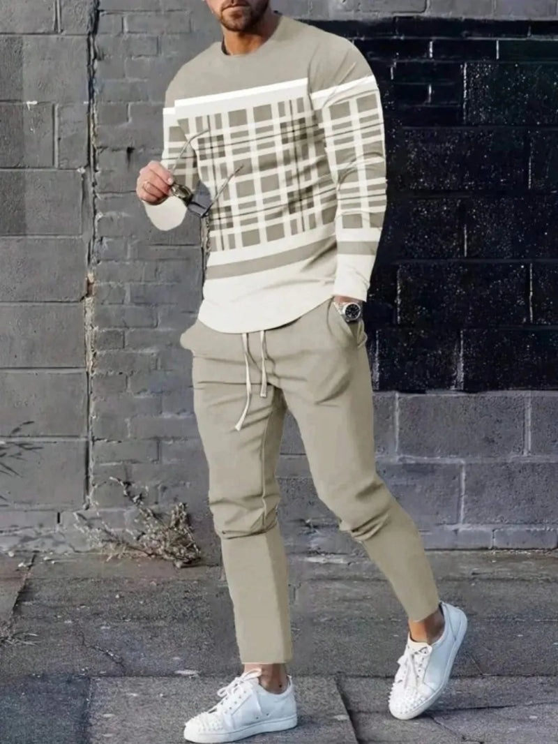 Person wearing a patterned sweater and beige pants against a brick wall.