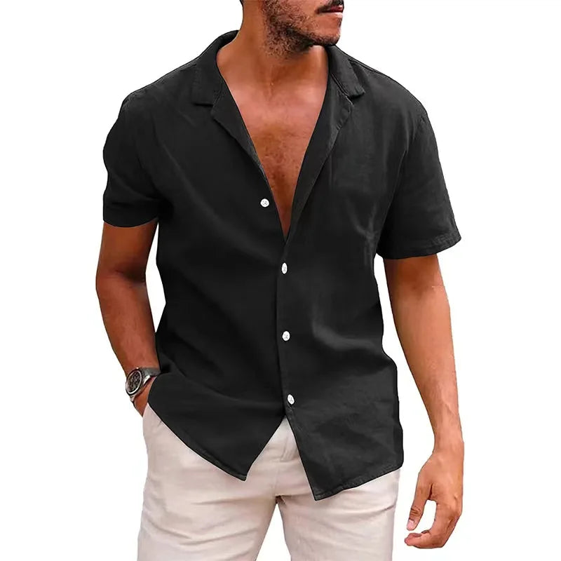 Man wearing a black short-sleeve button-up shirt with white pants on a white background