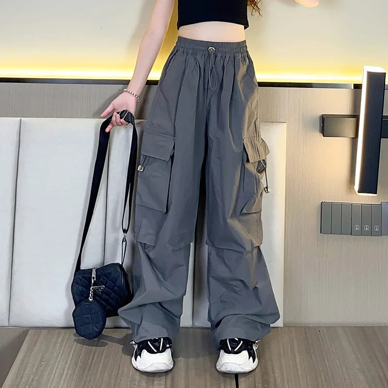 Person wearing gray cargo pants in a room with a white couch and wall-mounted lamp.
