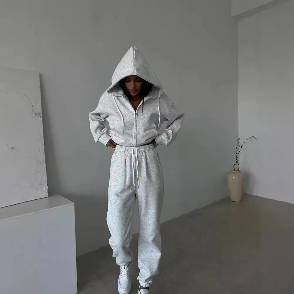 Person wearing a gray tracksuit in a minimalistic room.