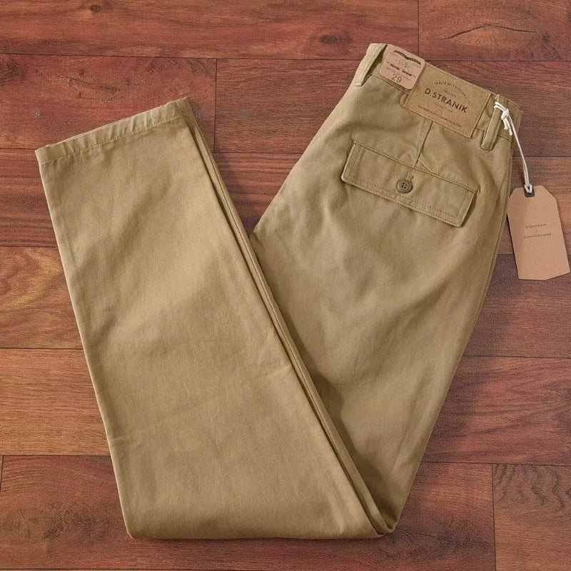 Beige pants on a wooden floor with a brand tag attached.