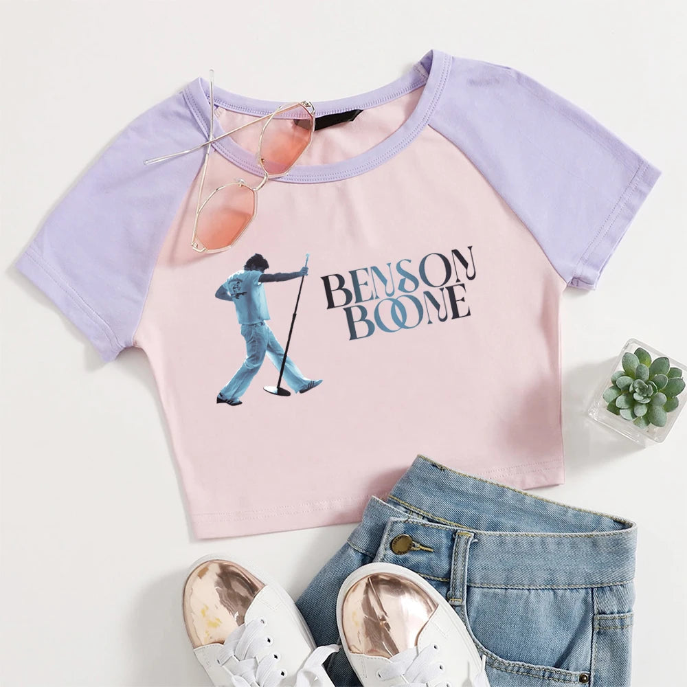 Pink and purple t-shirt with 'Benson Boone' graphic, sunglasses, jeans, and sneakers on a white background