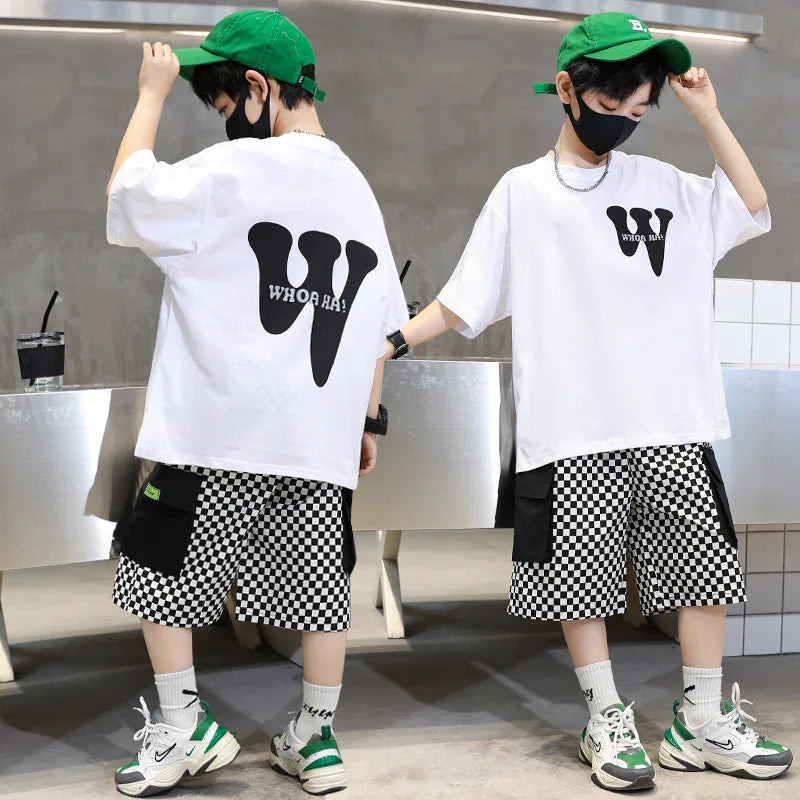 Two people wearing matching outfits with white t-shirts and checkered shorts in a modern indoor setting.